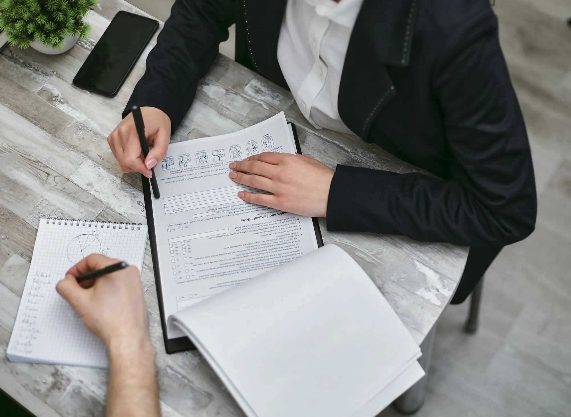 Two people reviewing printed documents and taking notes.