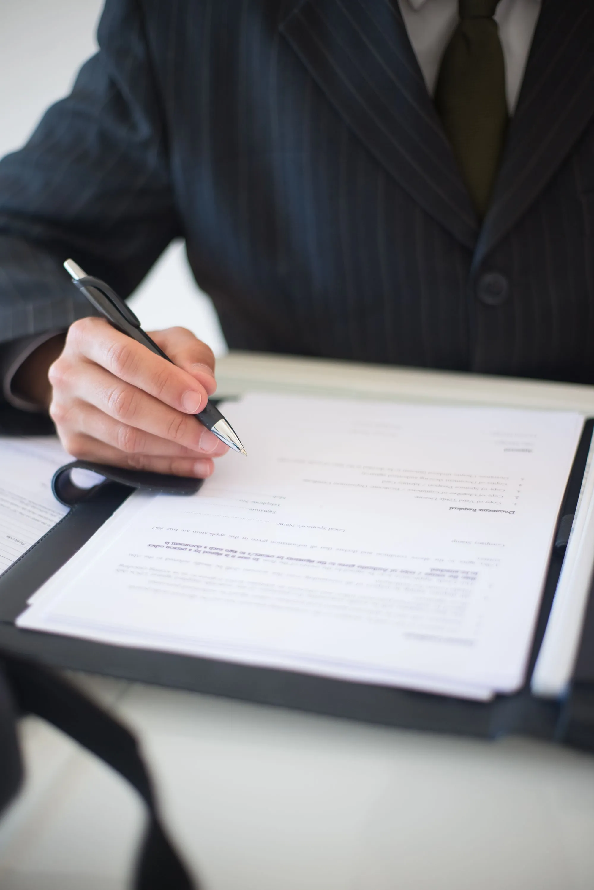 A closing specialist signing a loan document at a desk.